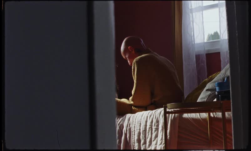 A little girl in a room talking to a bald woman who is sitting on the bed