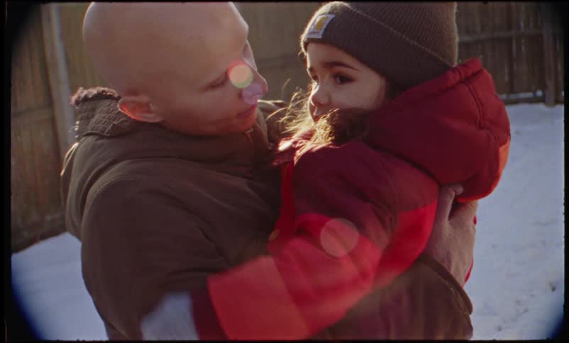A mother holding her daughter in the snowy backyard as she points to the sky
