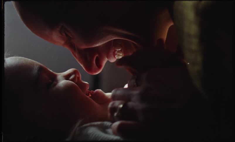 Happy mother playing with her baby in a dimly lit room at home