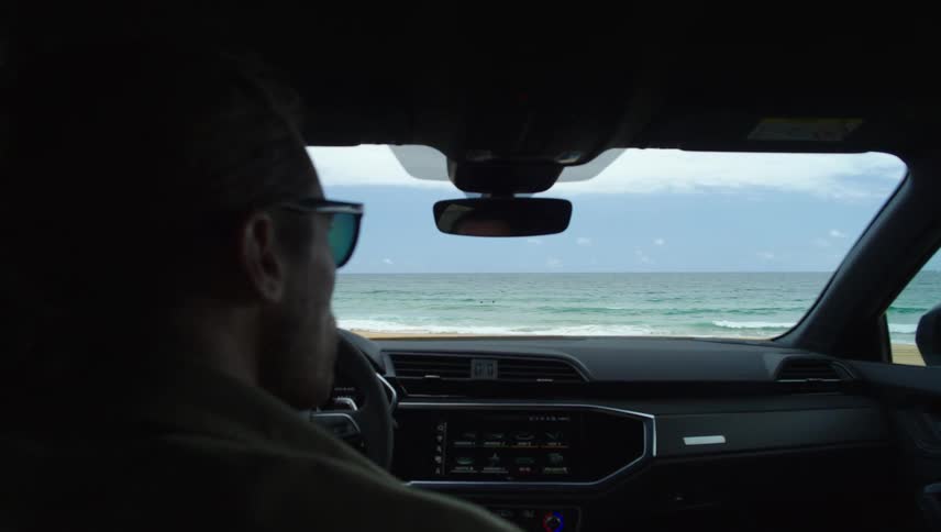 View of the interior of a vehicle highlighting the dashboard and windshield that reveals the sea in front