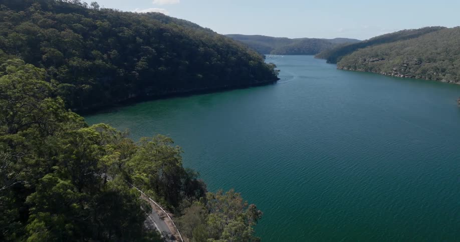 Aerial view of a serene river flanked by dense forested hills