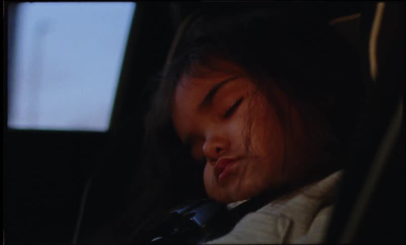 Close up of the face of a girl asleep in the back of a moving car