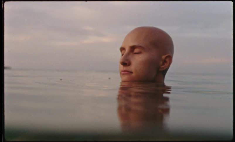A person is swimming in a body of water at dusk
