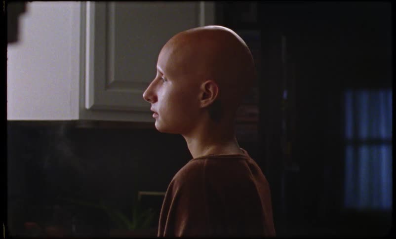 A person with a bald head contemplates while cooking food in a kitchen
