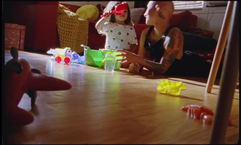 A mother and daughter on the floor of a living room playing with toys