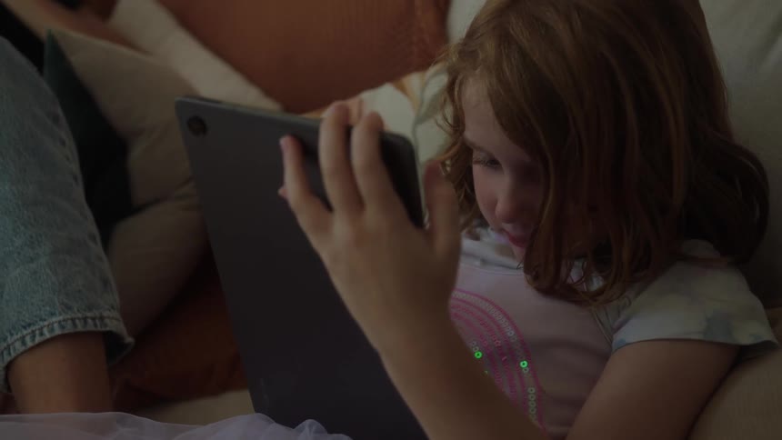 A girl resting on a couch looking at a tablet