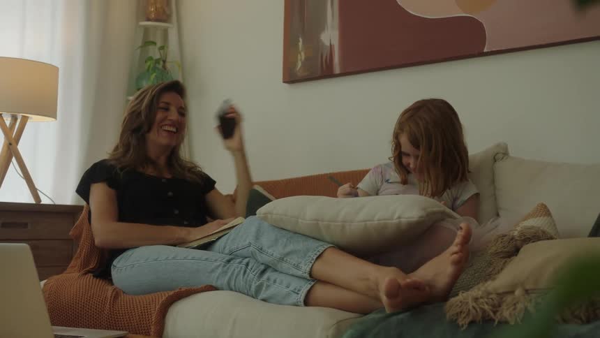 Mother sitting talking on the phone and her daughter next to her