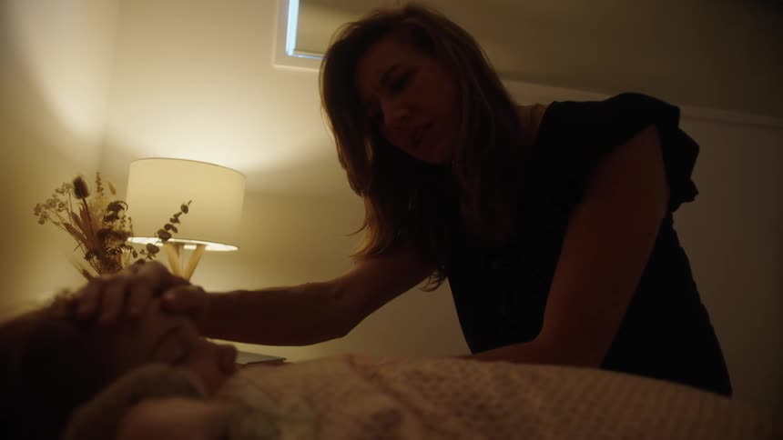 A mother gently comforts her young daughter as she lies in bed