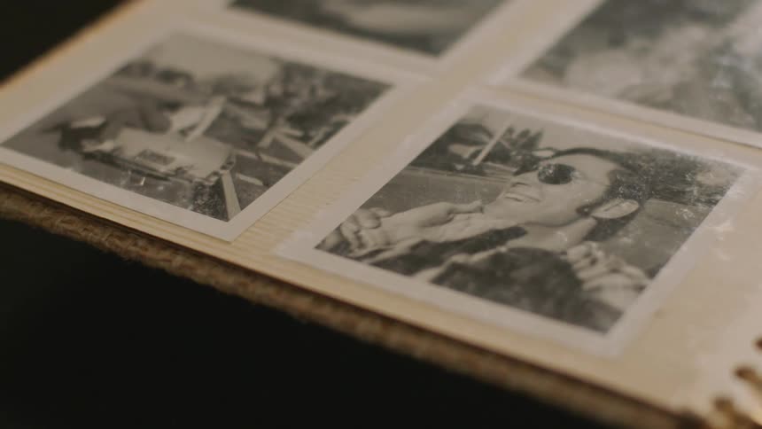 Photo album with old black and white photos of a man laughing and a woman posing