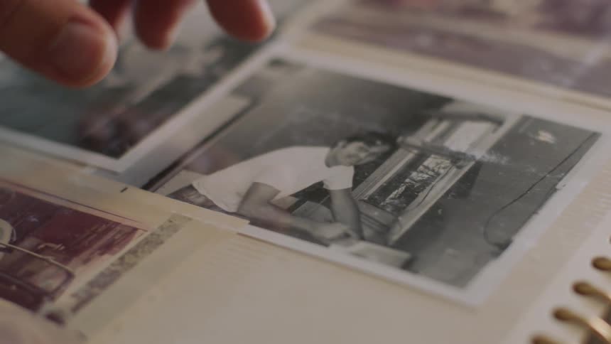 A hand points to a black and white photograph in an album