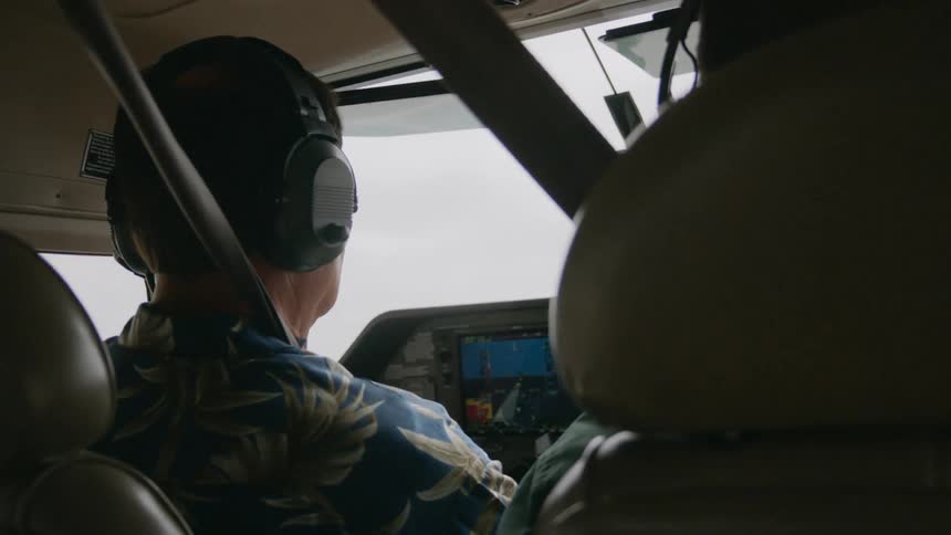 Male pilot sits in aircraft with a passenger in the front seat