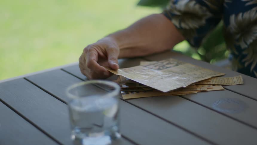 Hand holding a reading paper and a glass cup with water next to it