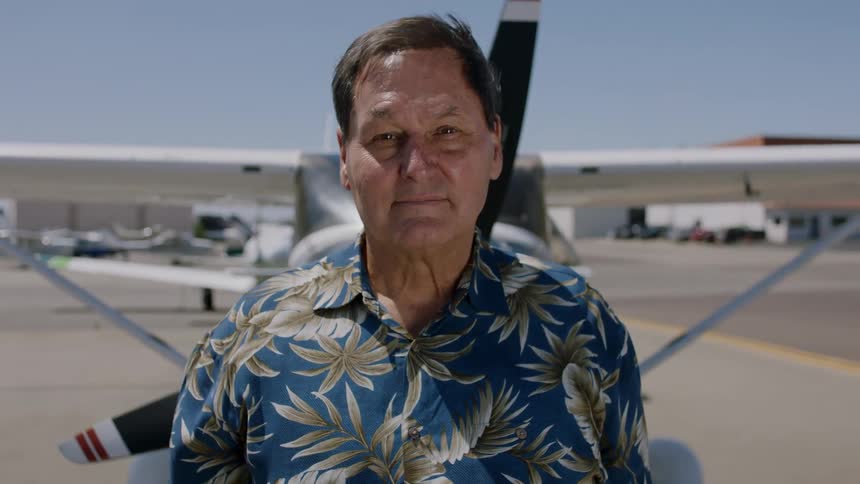A man stands in front of a plane at an airport