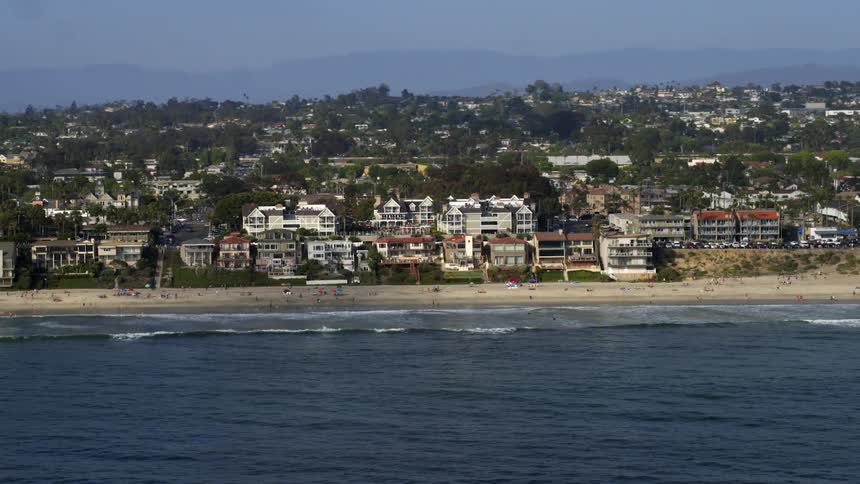Coastal town on the edge of a beach with the silhouette of mountains on the horizon