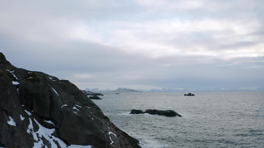 Waves reach the snowy black mountains