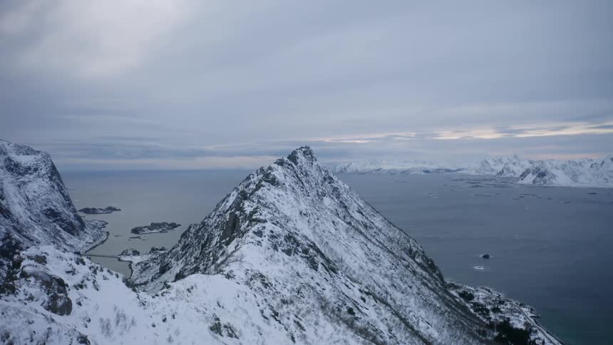 Aerial landscape of a steep mountain covered in snow by the sea