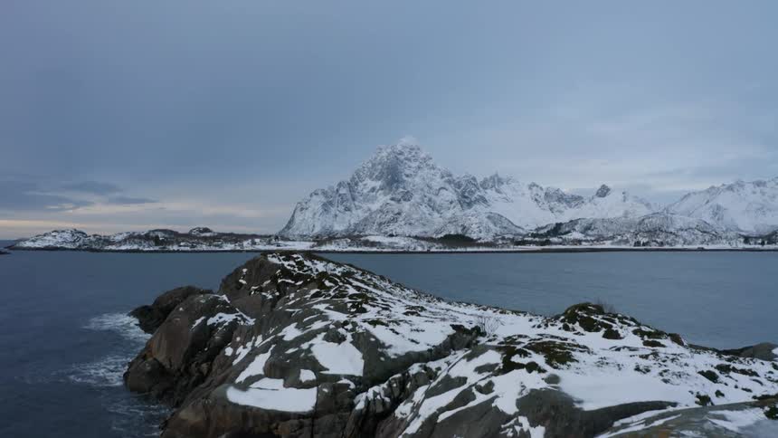Landscape of rocks surrounded by the sea covered by snow on a cloudy day