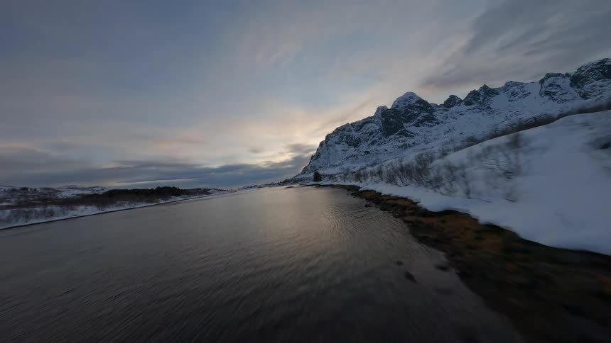 Aerial landscape of mountains covered in snow and surrounded by an extensive sea