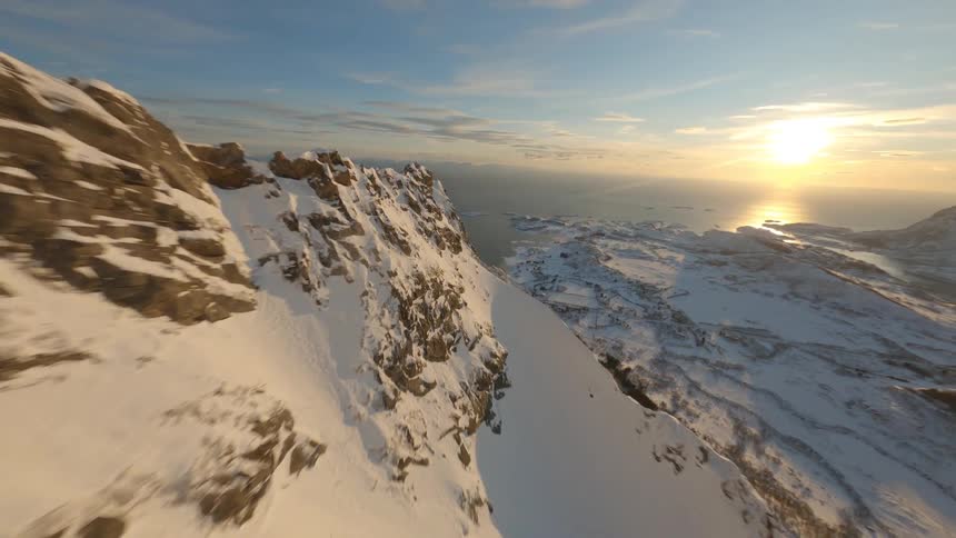 An aerial view of a snow covered mountain range landscape at dusk