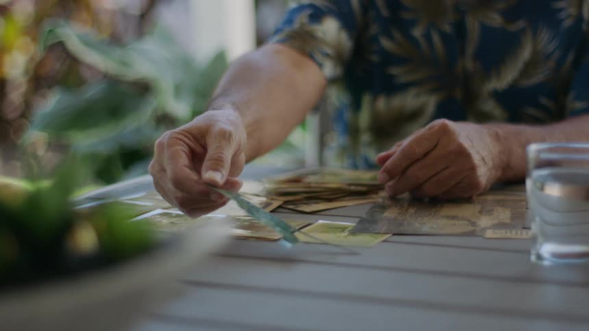 An old man places a scrap of paper on a table