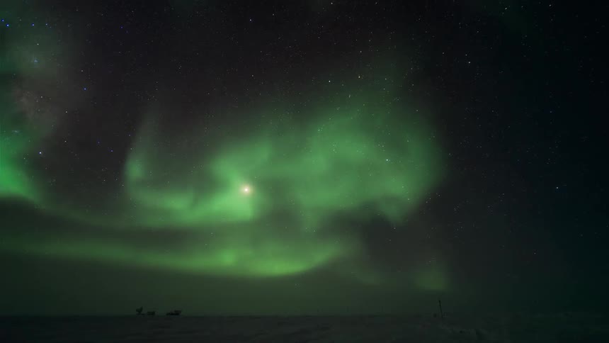 A man appears around a flat area while a green aurora rages in the sky