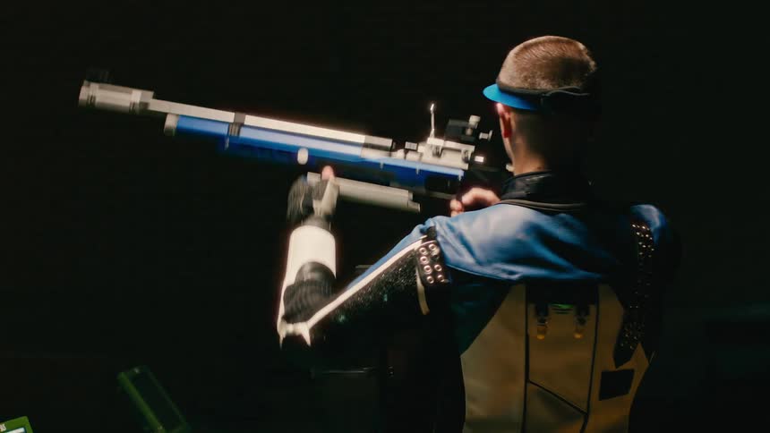 Man picks up a large long gun and looks through the sight to aim