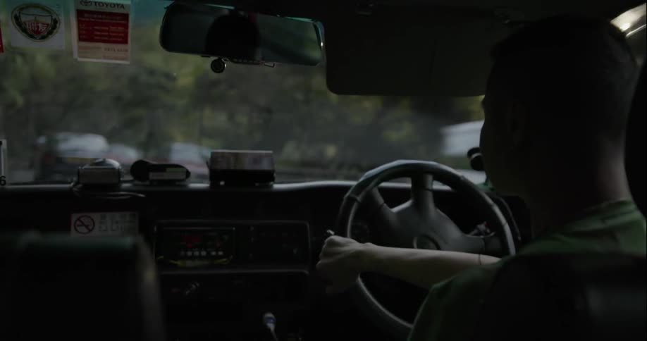 A man is driving a car down a road with traffic
