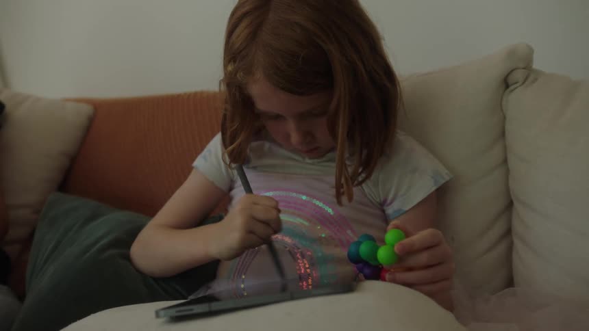 Girl sitting on a sofa drawing on a tablet
