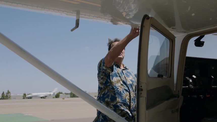 A man inspects the wing of a small aircraft