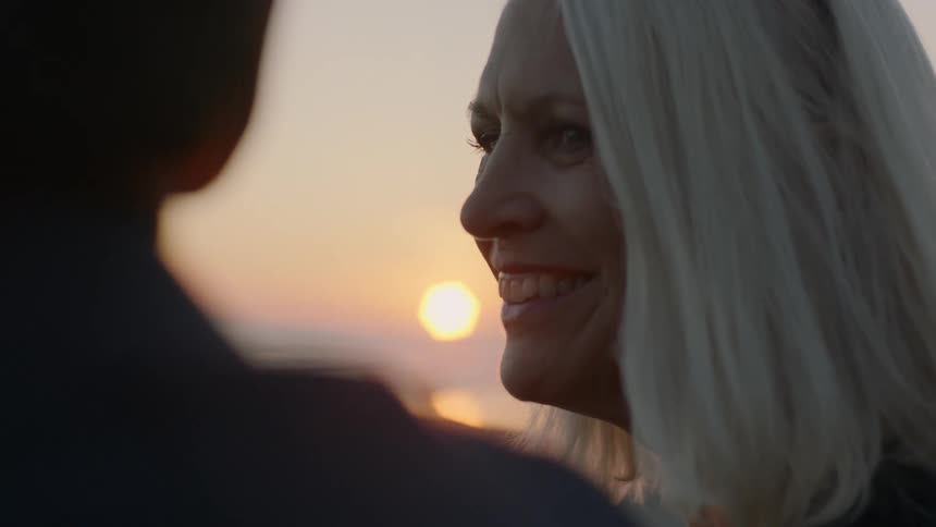 A woman smiles at a man while on the beach