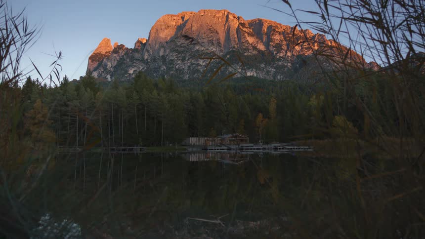 A house on a lake near a giant forest and mountain