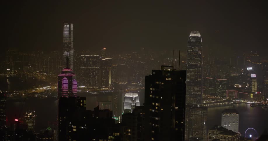 Several people on a rooftop in a large city at night