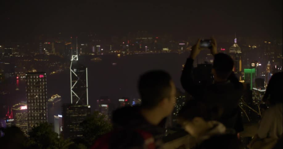People standing on a rooftop in a large city at night