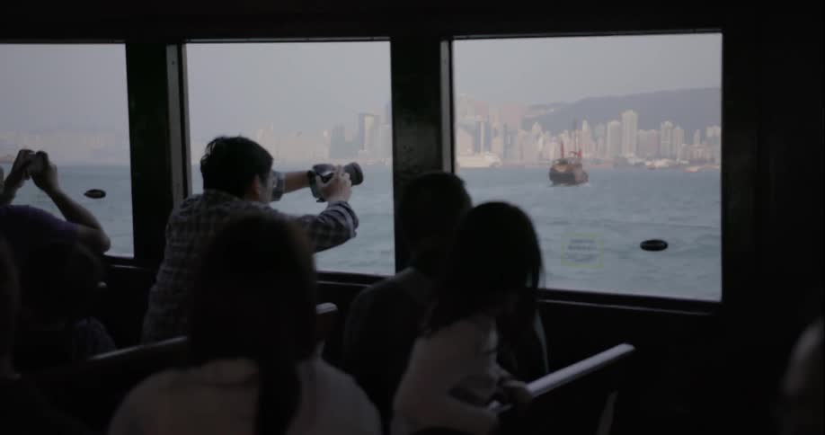 People taking photographs of city while riding on ferry boat