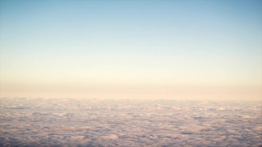 A vast expanse of clouds viewed from above with a gradient of warm colors