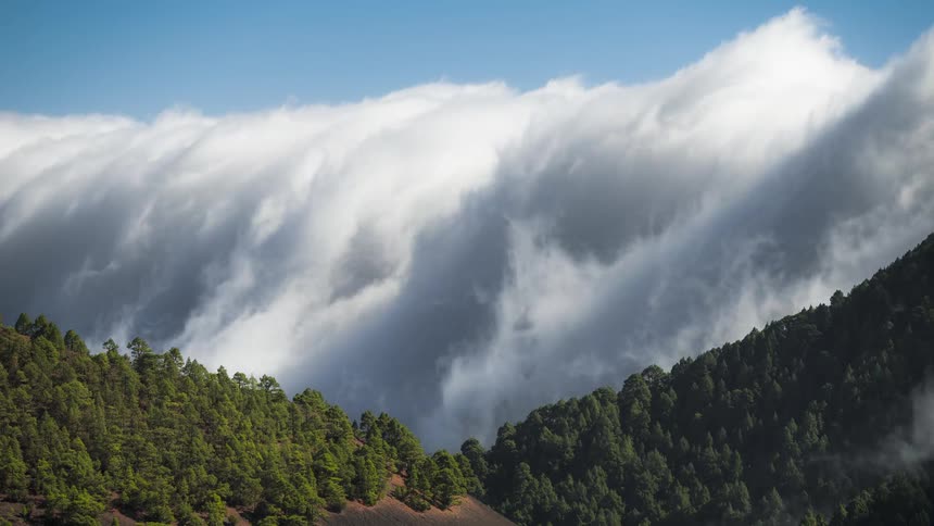 Time lapse of clouds rolling over the slopes of a mountain