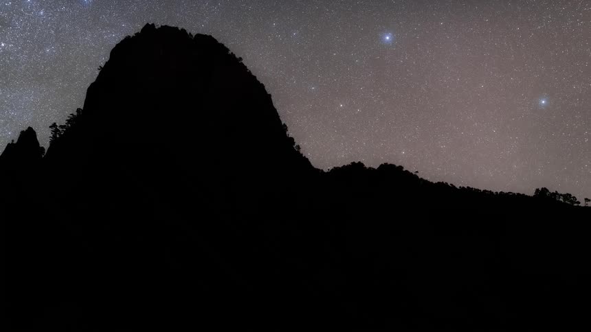 Time lapse of a starry sky over the dark silhouette of a mountain range