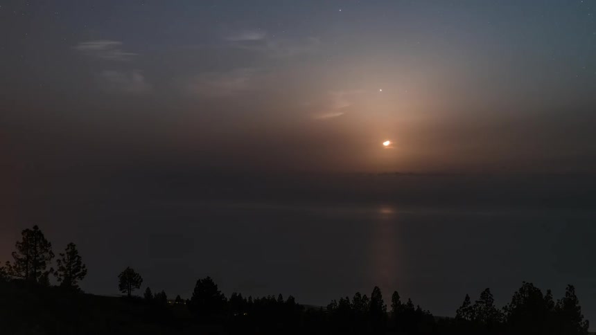 Panorama of a mountain silhouette by the sea with the sun setting on the horizon