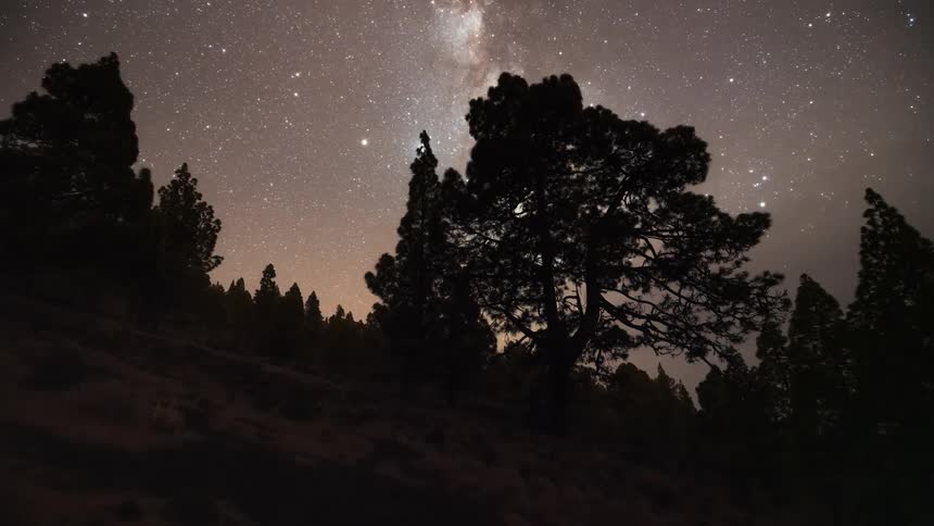 Scenery of a steep mountain with trees and the day dusk and the milky way appearing