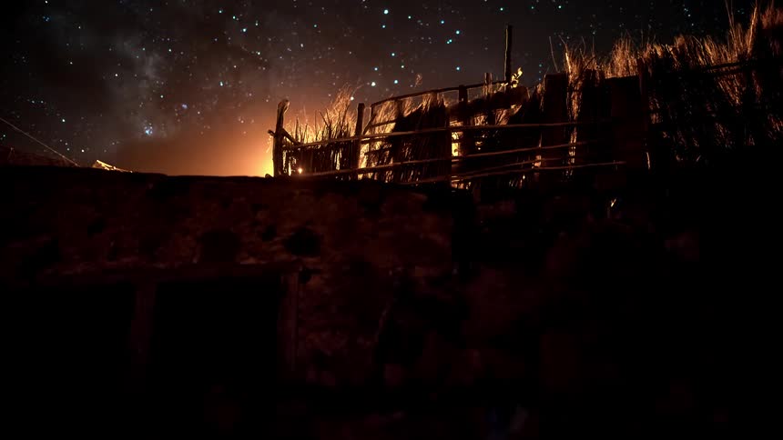 Time lapse of clouds rolling over a rural scene under a starry sky