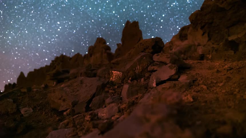 Eroded rock wall of a mountain and a night sky with the milky way visible