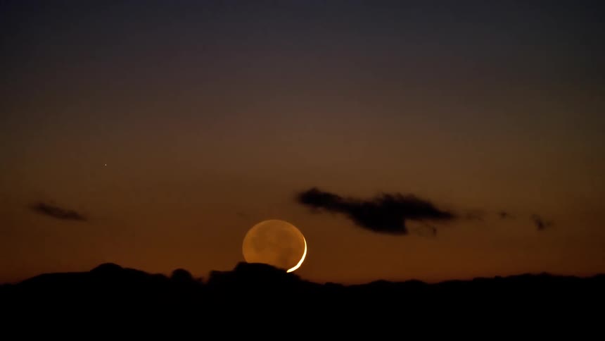 Night landscape with the moon descending on the horizon and clouds passing by