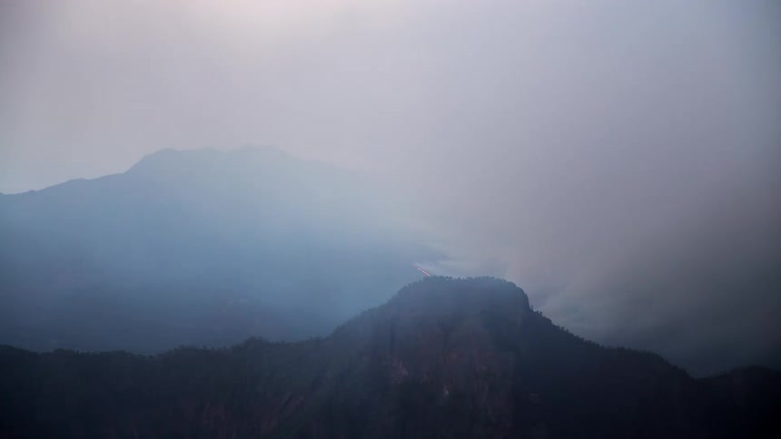 Time lapse of dawn over a volcanic landscape covered with erupting lava and smoke