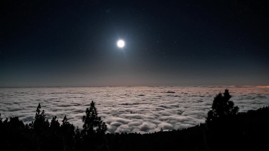 Night landscape with the bright moon descending in the sky and a vast sea of clouds below