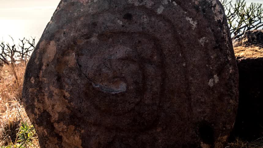 A time lapse shows a large stone with a spiral drawn upon it