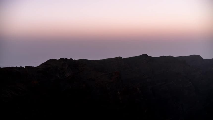 Time lapse of sunset falling over a barren mountain range