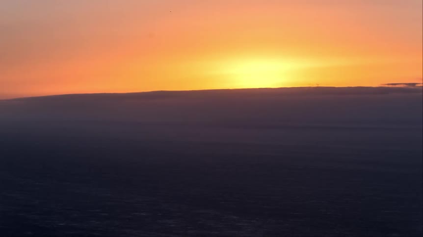 Clouds floating over a gentle ocean as the sun goes down
