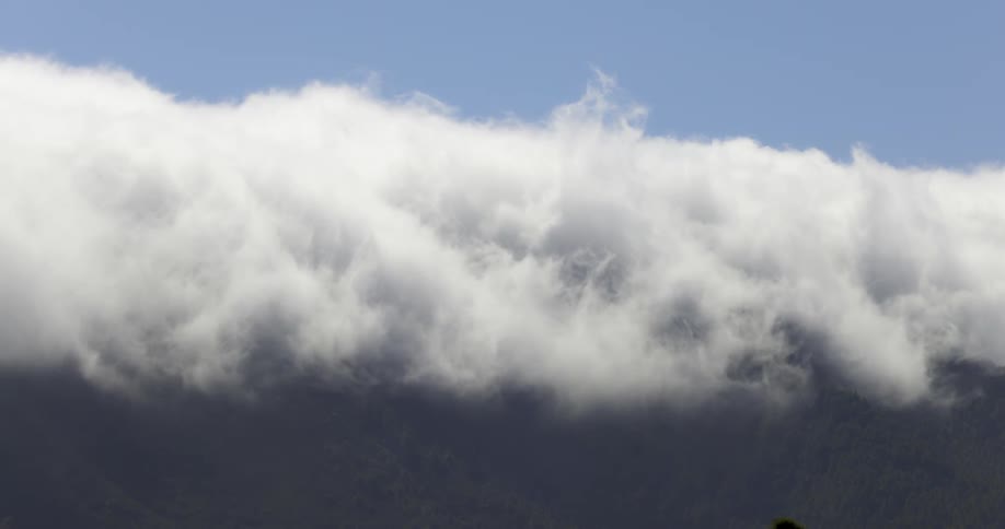 Vast expanse of white clouds above a mountain range against a clear blue sky