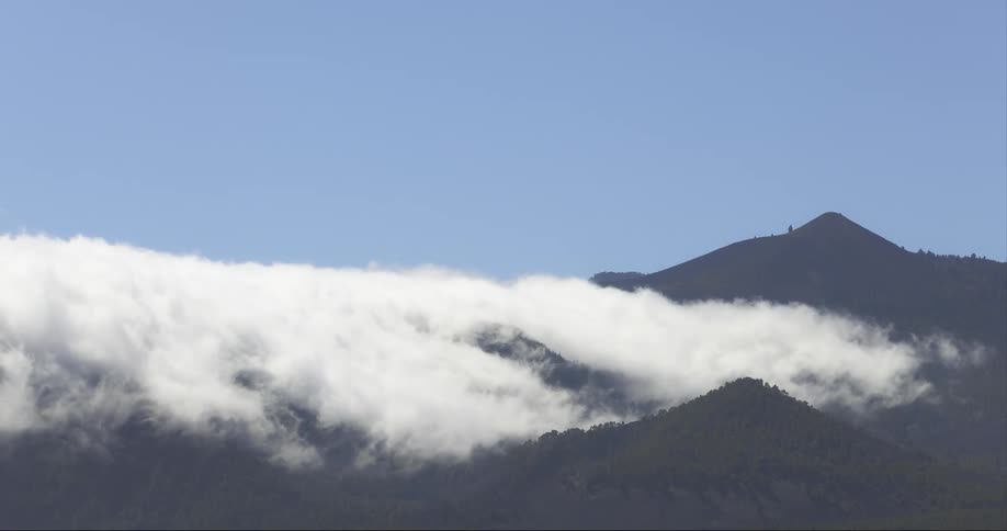 Mountain range with peaks partially obscured by a dense layer of low clouds