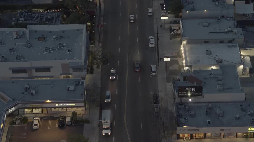 An overhead view of a city and vehicles driving around at evening time